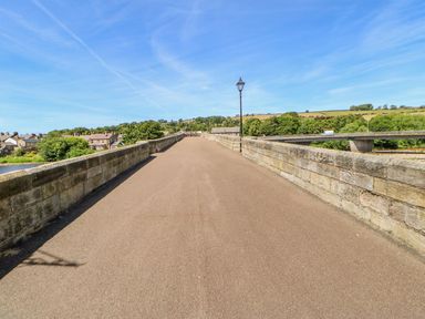 A bridge with houses and trees visible in the background at The Railway Apartment in Hexham