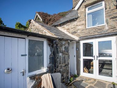 An outdoor view of The Ingle with stone walls and doors in Barmouth