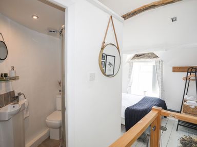 A bathroom with a sink and toilet in view and a bed behind at The Ingle in Barmouth