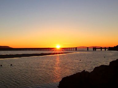A sunset view with bridges and water at The Ingle in Barmouth