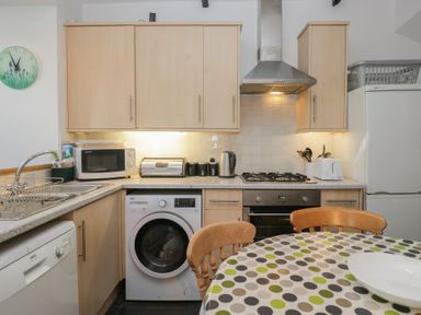A kitchen with appliances and a round table at Cloud Cottage in Ambleside