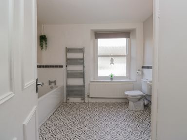 A bathroom with a bathtub, toilet, and window at Cloud Cottage in Ambleside