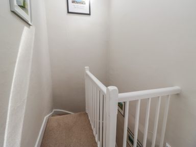 A staircase with a handrail and framed pictures at Cloud Cottage in Ambleside