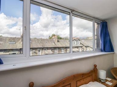 A view of rooftops through a window in a bedroom at Cloud Cottage Ambleside