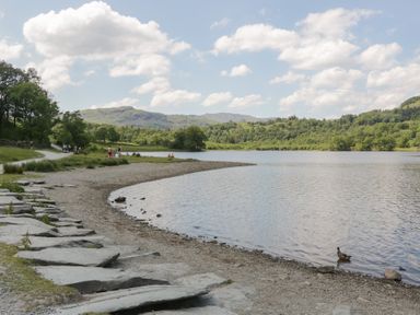 A lake with a stone path and trees at Cloud Cottage, Ambleside
