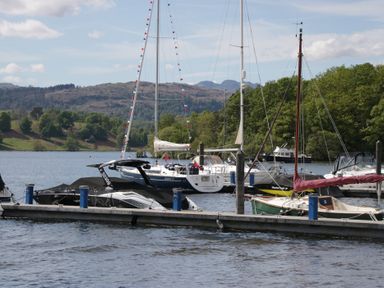 Boats on a dock in a lake with mountains in the background at Cloud Cottage Ambleside