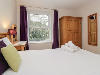 A bedroom with a bed, wardrobe, and mirror at Cloud Cottage Ambleside