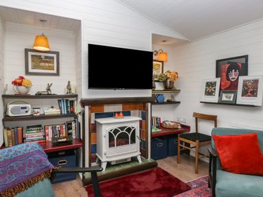 A living room with a television and bookshelf at Moon Cottage White Cross Bay Holiday Park near Troutbeck Bridge