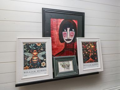 Artworks on a shelf including portraits and nature-themed prints at Moon Cottage White Cross Bay Holiday Park near Troutbeck Bridge