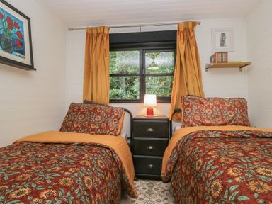 A bedroom with two beds and a bedside table at Moon Cottage near White Cross Bay Holiday Park near Troutbeck Bridge