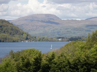 A view of a lake with trees and mountains in the background at Moon Cottage in White Cross Bay Holiday Park near Troutbeck Bridge