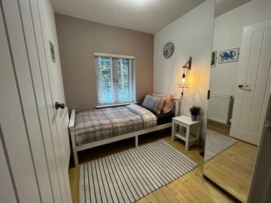 A bedroom with a bed, nightstand and lamp at Dolwen in Caernarfon
