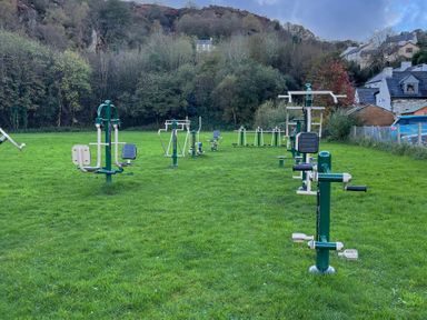 An outdoor gym with exercise equipment on grass at Dolwen in Caernarfon