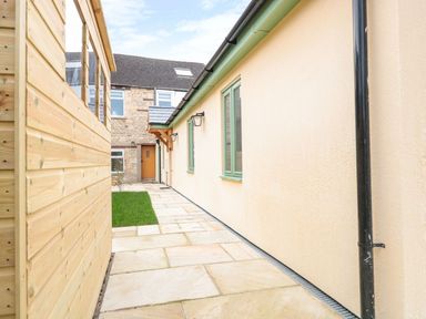 An outdoor pathway between a wooden shed and a stone wall at The Old Sorting Office