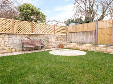 A garden with a bench and stone wall at The Old Sorting Office 