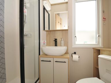 A bathroom with shower, sink, toilet, and mirror at Eden Way 47