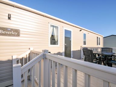 A mobile home with a deck and seating area at Eden Way 47 Par