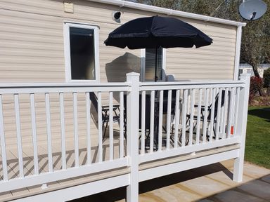 An outdoor area with a table and chairs under a parasol at Par Sands Holiday Park - 6388, Par