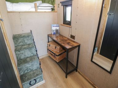 A bedroom with a bed, stairs, and a table with baskets at GiGi's Horsebox in Evesham