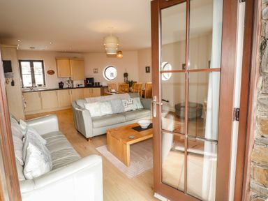 A living room with a sofa and kitchen area at Awel y Môr in Burry Port