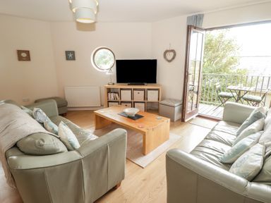 A living room with a television and sofas at Awel y Môr in Burry Port
