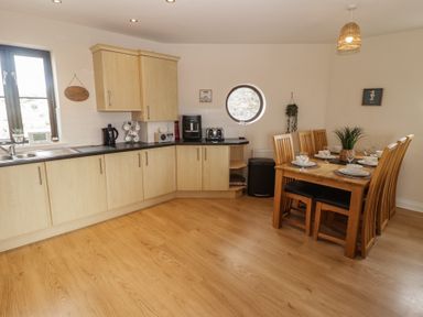 A kitchen with a dining table and chairs at Awel y Môr in Burry Port