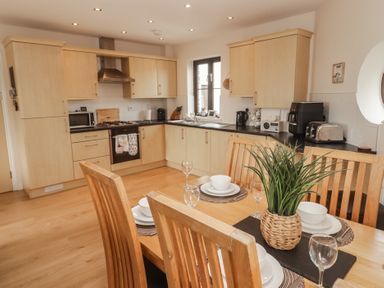 A kitchen with cabinets, stove, and dining table at Awel y Môr in Burry Port