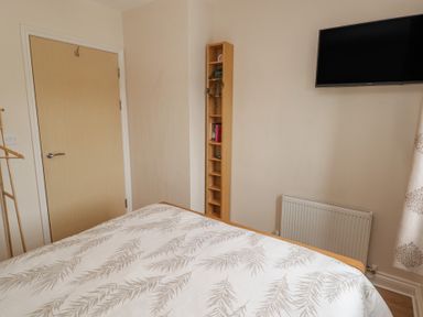 A bedroom with a bed and a television at Awel y Môr in Burry Port