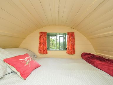 A bedroom with a bed and window at Goldfinch in Panson Mill near Ashwater