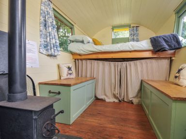 A bedroom with a lofted bed and benches at Prudence in Panson Mill near Ashwater
