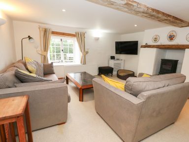 A living room with a sofa, coffee table, and television at Bubbs Cottage
