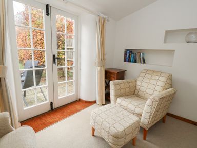 A snug with an armchair and footstool at Bubbs Cottage