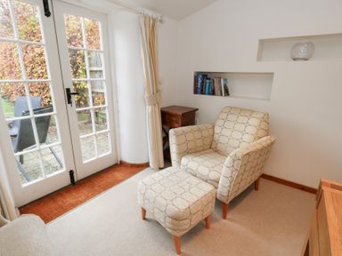 A snug with an armchair and footstool at Bubbs Cottage