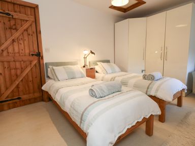 A bedroom with two beds and a wooden door at Bubbs Cottage