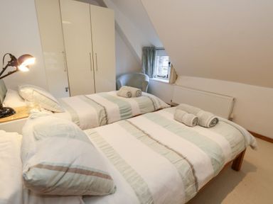 A bedroom with two beds and a wardrobe at Bubbs Cottage