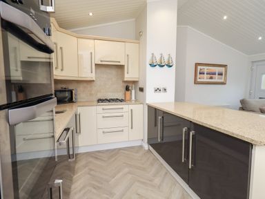 A kitchen with cabinets, a refrigerator, and a countertop at Laughing Duck in Troutbeck Bridge