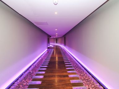 A corridor with wooden walkway and purple lighting at Costal Lodge at Seaham Hall, Seaham