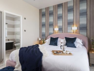 A bedroom with a bed, tray, and adjacent bathroom at Costal Lodge at Seaham Hall, Seaham