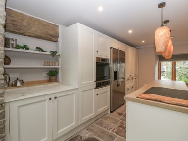 A kitchen with white cabinets and a stone countertop in a 3 bed property