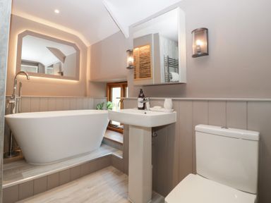 A bathroom featuring a bathtub, sink, toilet, and mirror at a 3 bed property