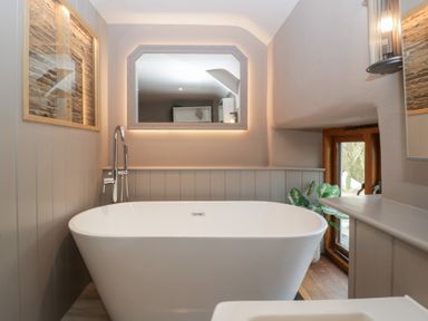 A bathroom with a bathtub and mirrors at 3 bed property