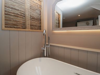 A bathroom with a bathtub and mirror in a 3 bed property