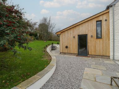 A garden with a gravel path leading to a wooden house at 3 bed property
