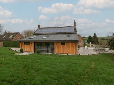 A house with solar panels and a patio area in the garden