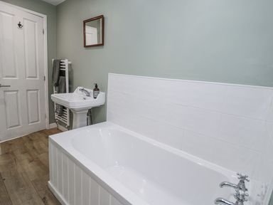 A bathroom with a bathtub, sink, and towel radiator at Haulfryn in Dolwyddelan