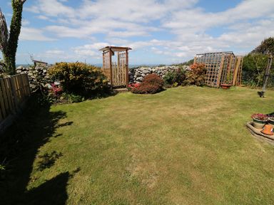 A garden with grass, flower beds, and trellis structures at Goetra