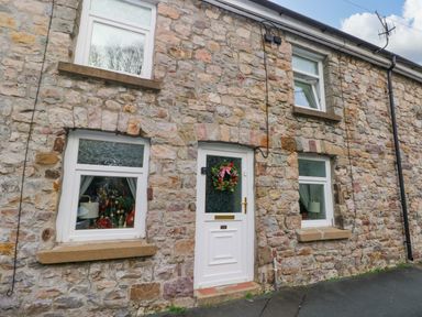 An outdoor view of a stone cottage with a front door and windows at Tawe Cottage Swansea