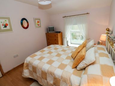 A bedroom with a bed and a dresser at Tawe Cottage in Swansea