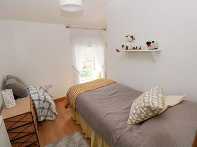 A bedroom with a bed and toys on a shelf at Tawe Cottage Swansea