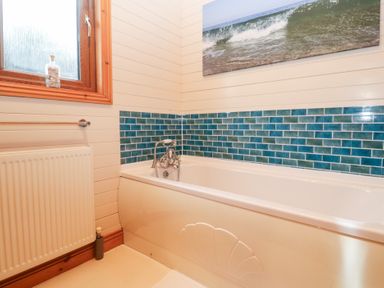 A bathroom with a bathtub and mosaic tiles at Lamorna in Sennen